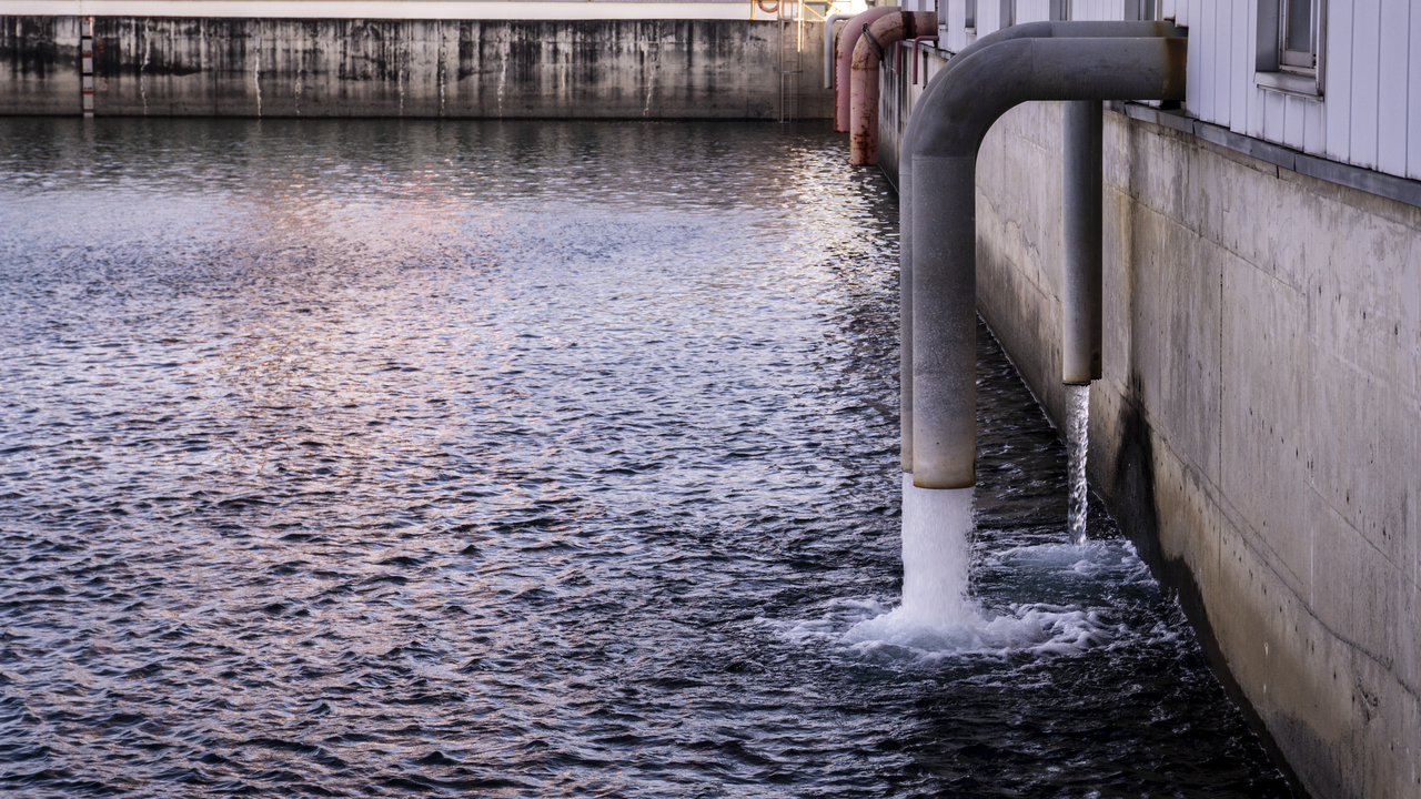 Treated water discharging from large industrial pipes into a collection pool at a factory or treatment facility. Credit: Getty Images